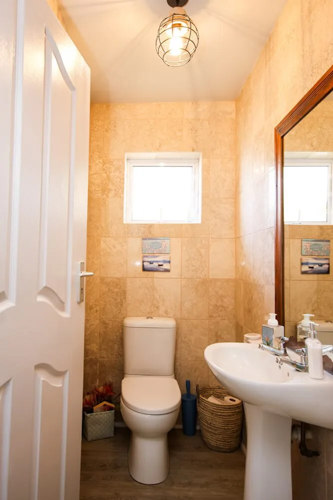 Separate guest toilet with terracotta tile, pedestal sink and wood-framed mirror, Unit One, Die Hawehuis